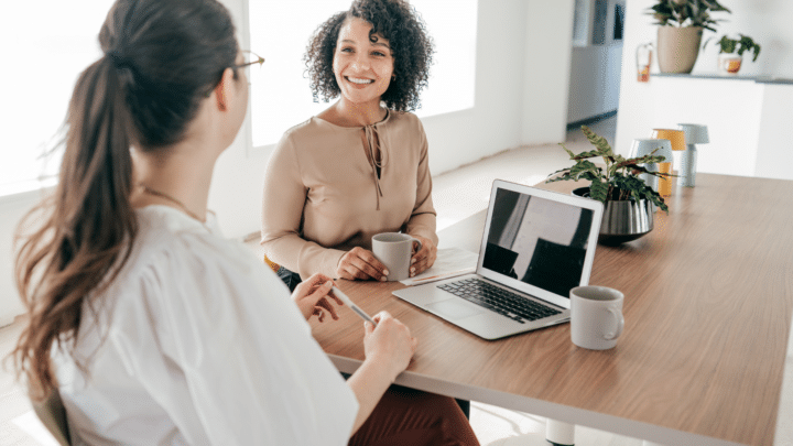 Deux femmes discutent autour d’un bureau.