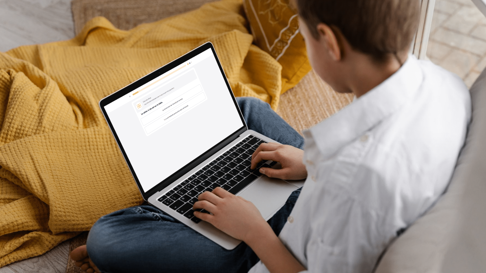 Un élève installé confortablement chez lui s'entraîne sur le parcours Expression écrite du Projet Voltaire sur son ordinateur portable.