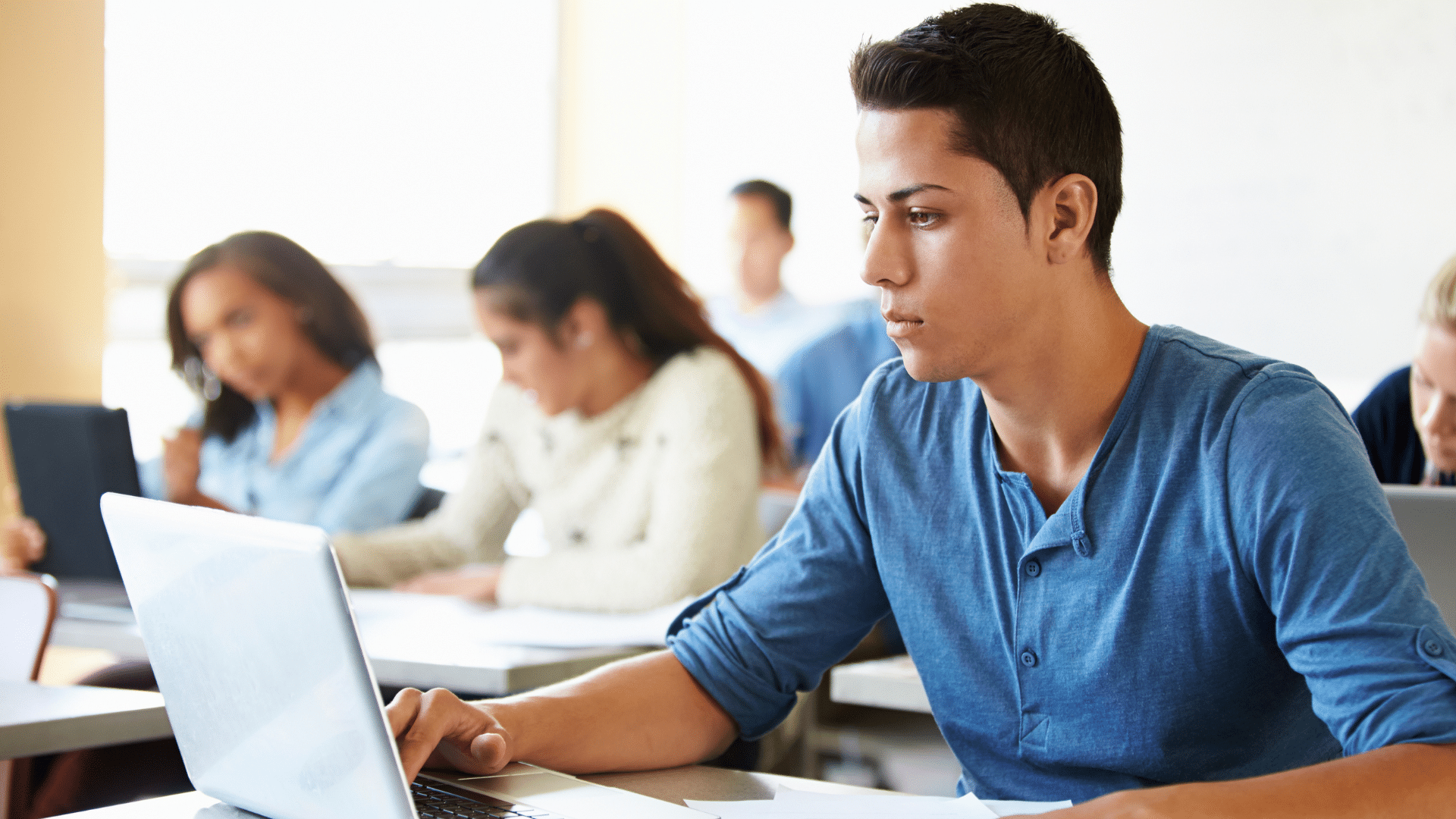 Un lycéen travaille sur ordinateur dans une salle de classe.