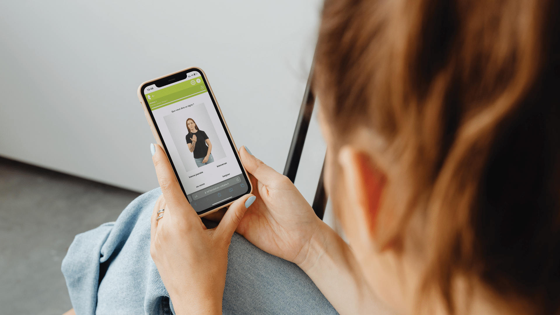 Une femme utilise son téléphone portable et se renseigne sur la langue des signes française.
