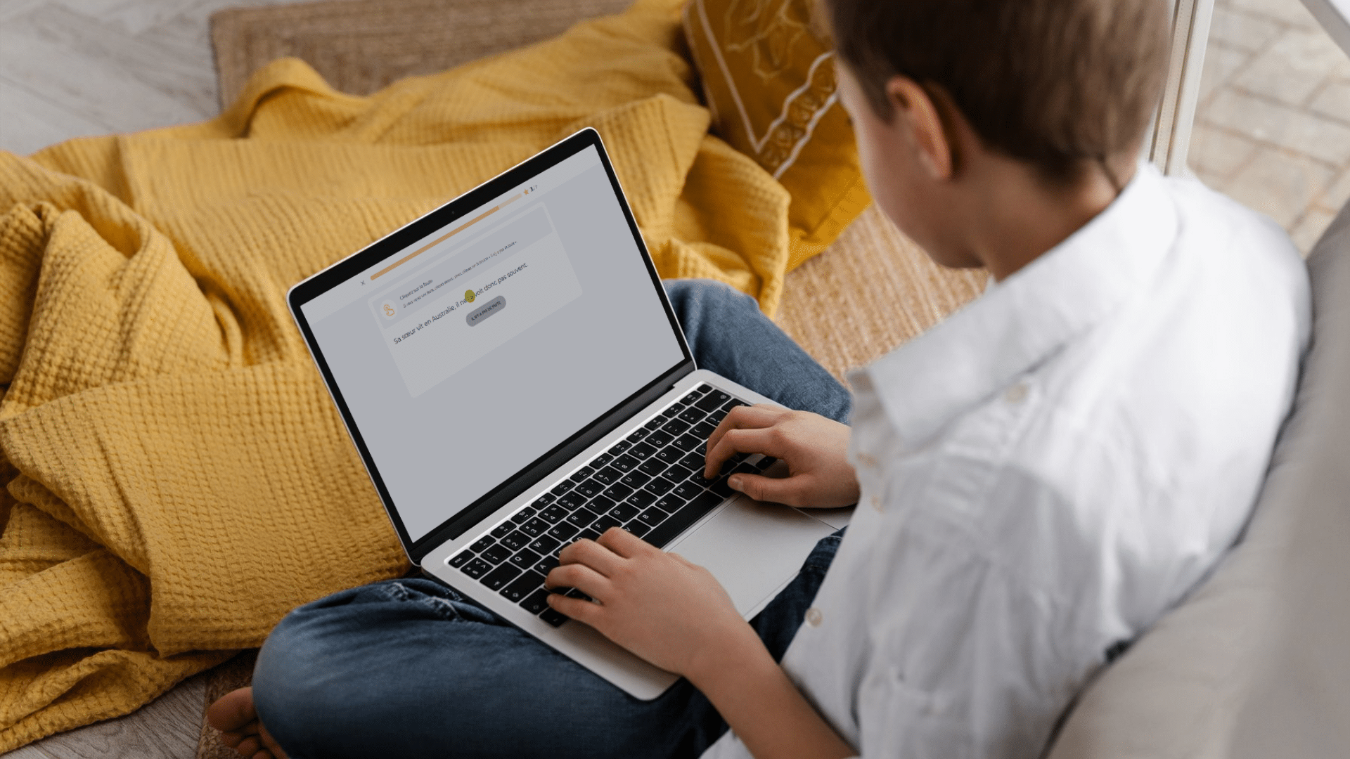 Un élève assis chez lui s'entraîne sur la plateforme Projet Voltaire depuis son ordinateur portable.