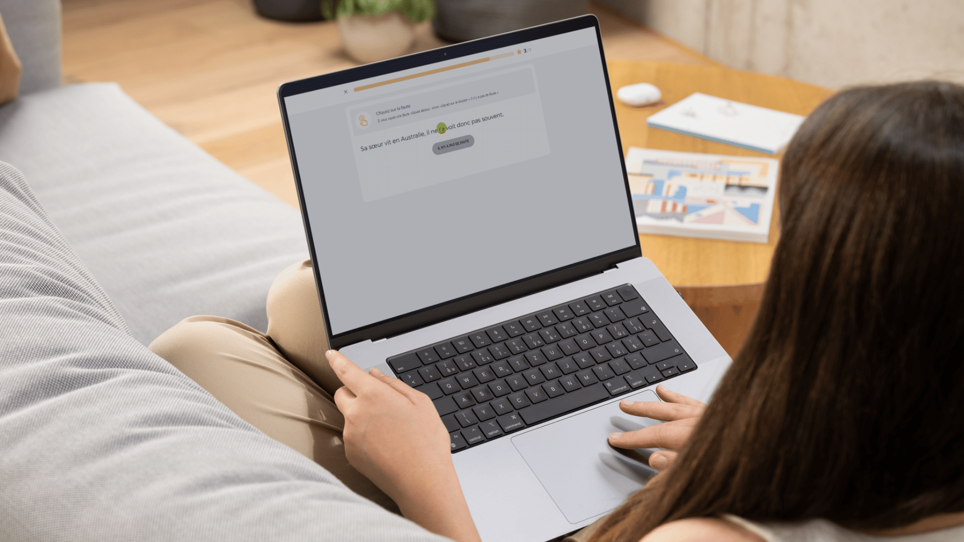 Une étudiante s'entraîne avec le Projet Voltaire, installée confortablement sur un canapé avec son ordinateur portable.